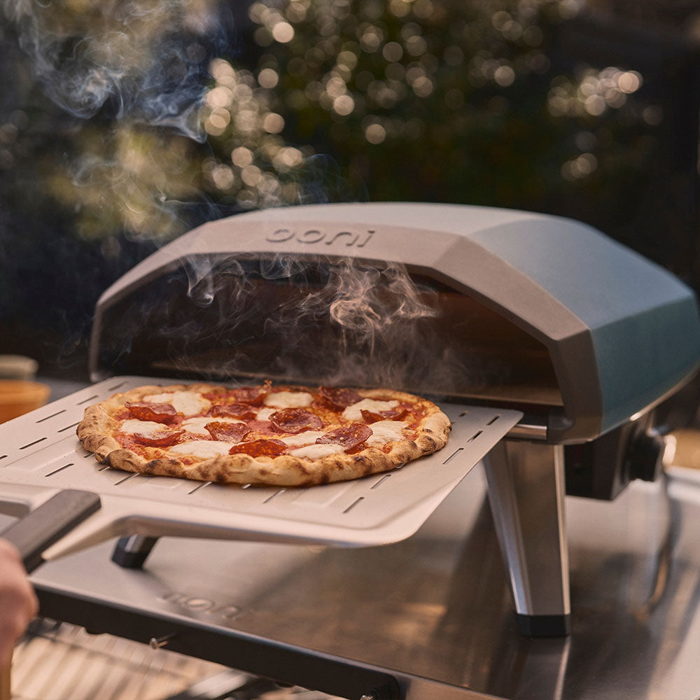 pepperoni pizza being retrieved on a pizza peel from ooni koda 2 in slate blue #variant-2