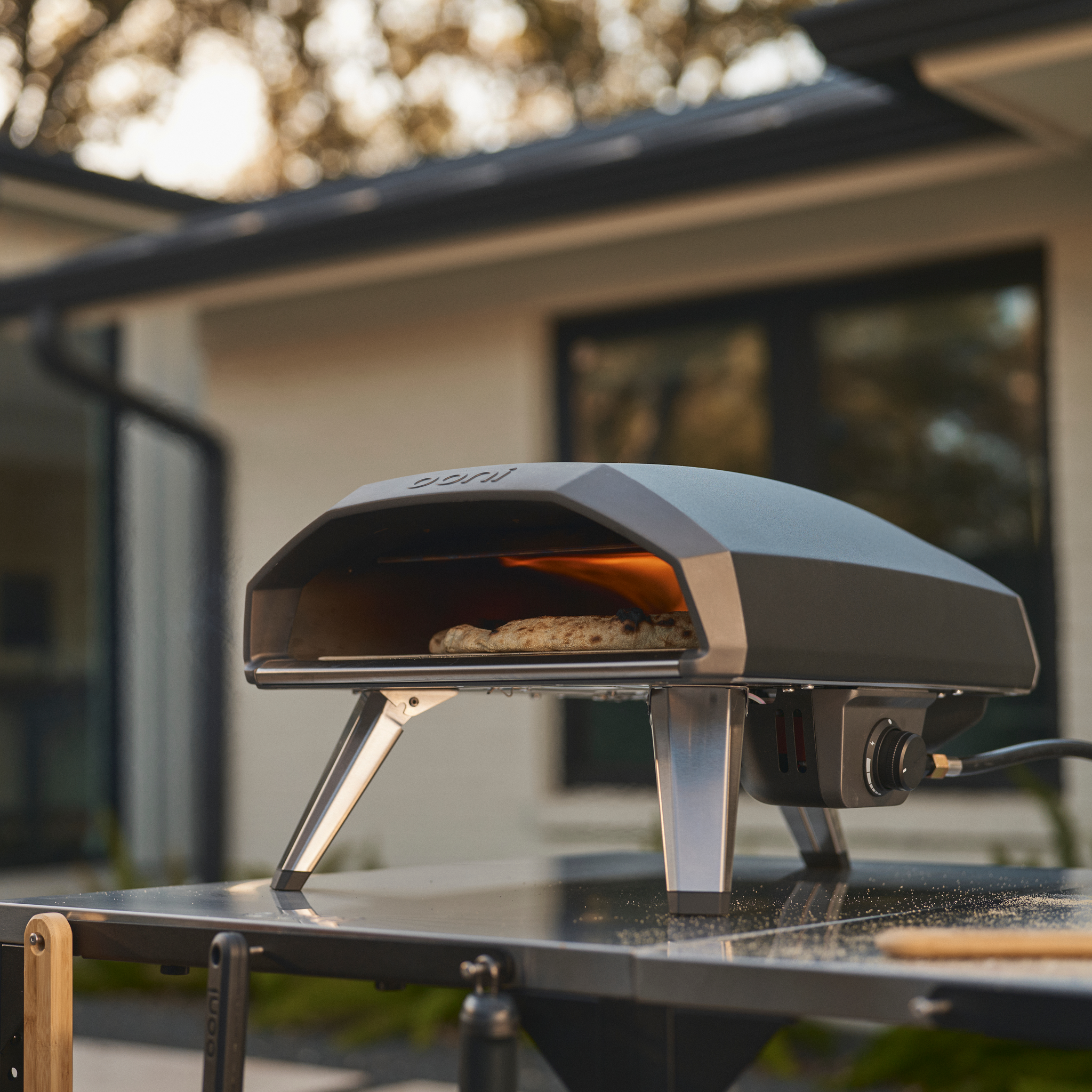 Ooni koda 2 pro cooking pizza outdoors on a pizza oven table #variant-1
